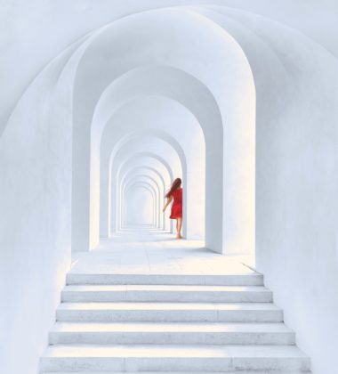 woman-in-red-dress-standing-in-white-arch-building-1874726